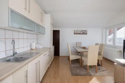 a kitchen with a sink and a table with chairs at Apartman Radoš in Kupres