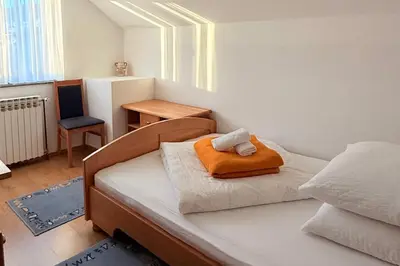 a bedroom with a bed with an orange pillow on it at Gradska Kavana Guest House in Kupres