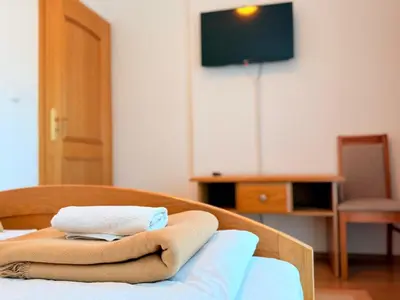 a room with a bed with a towel and a tv at Gradska Kavana Guest House in Kupres