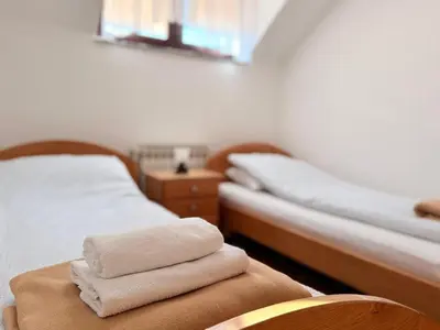 two beds in a room with towels on a chair at Gradska Kavana Guest House in Kupres