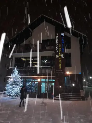 a person walking in front of a building with a christmas tree at Gradska Kavana Guest House in Kupres