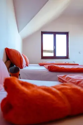 a room with four beds with orange pillows at Guesthouse Nevenko in Kupres