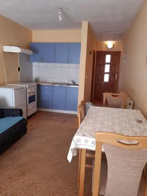a kitchen with blue cabinets and a table and a table and chairs at Apartman Aurelia in Bihać