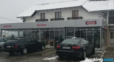 two cars parked in a parking lot in front of a store at Motel Restoran Gurman in Banja Luka