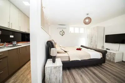 a bedroom with a large bed and a kitchen at Studio apartman Centar in Banja Luka