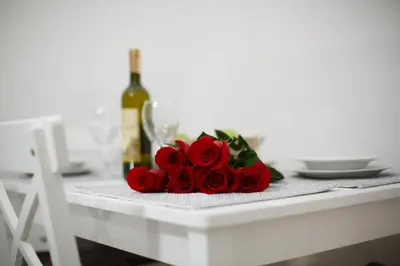 a table with a bunch of red roses and a bottle of wine at Apartman Centar in Banja Luka