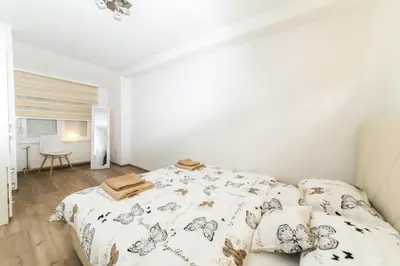 a white bedroom with a bed and a chair at Apartman Top Spot in Banja Luka