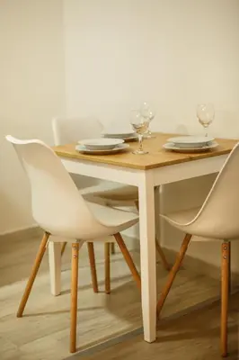 a wooden table with two white chairs and a table with wine glasses at Apartman Top Spot in Banja Luka