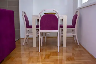a dining room table with purple chairs on a wooden floor at Apartman Marija in Banja Luka