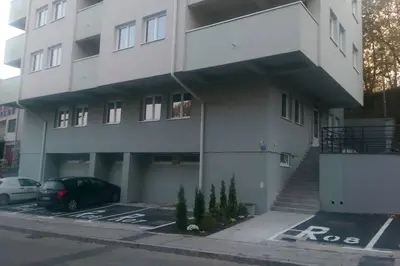 a building with a car parked in a parking lot at Apartman Marija in Banja Luka
