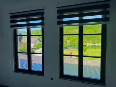 two windows in a room looking out at a yard at Hotel River View bihac in Lohovo