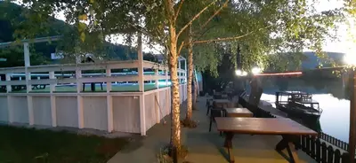 a group of tables and benches next to a river at Hotel River View bihac in Lohovo