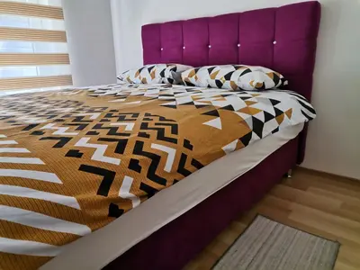 a bed with a purple headboard and pillows on it at Centar Apartman ENMI 111 in Banja Luka