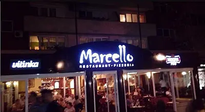 a sign for a restaurant with people standing outside at night at Apartman Penthaus u strogom centru Banja Luke in Banja Luka