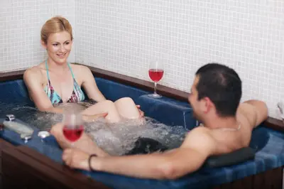 a man and woman in a bathtub with a glass of wine at Hotel Kardial in Teslić