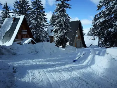 a house with a pile of snow in front of it at Vikendica A Vlasic in Vlasic