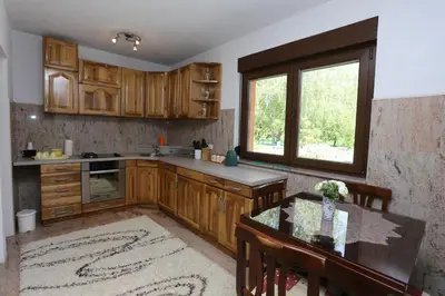 a kitchen with wooden cabinets and a table and a window at Villa Una Paradise in Bihać