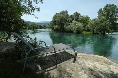 a bench sitting on a rock next to a river at Villa Una Paradise in Bihać
