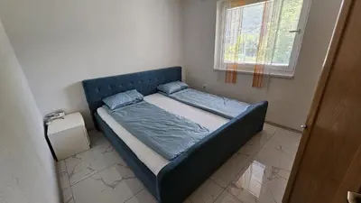 a blue bed in a room with a window at Apartman Nadija in Jajce