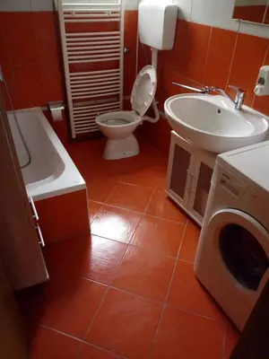 a bathroom with a toilet and a sink and a washing machine at Apartman Nadija in Jajce