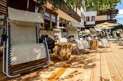 a group of chairs and tables on a wooden deck at Hotel Sunce Vlašić in Vlasic