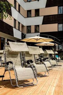 a group of chairs and umbrellas in front of a building at Hotel Sunce Vlašić in Vlasic