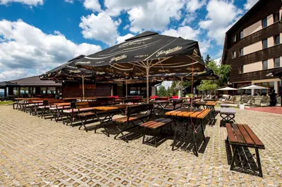 a row of tables and chairs under an umbrella at Hotel Sunce Vlašić in Vlasic