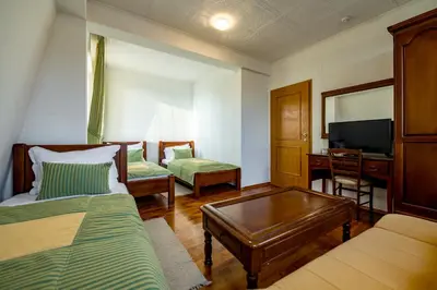 a room with two beds and a desk and a television at Hotel Sunce Vlašić in Vlasic