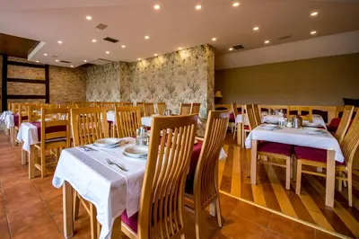 a dining room with white tables and chairs at Hotel Sunce Vlašić in Vlasic