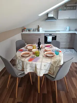a dining room table with chairs and plates and a bottle of wine at Apartmani Janjic in Banja Luka