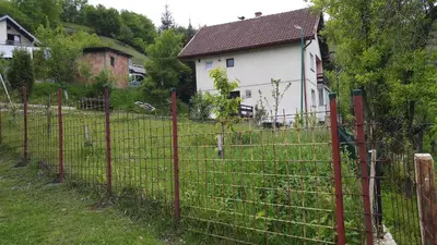 a fence in a yard next to a house at Vikend kuća Careva Ćuprija-apartman in Olovo