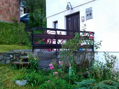 a porch of a house with a bench and flowers at Vikend kuća Careva Ćuprija-apartman in Olovo