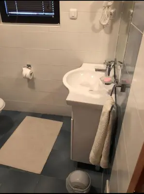 a white bathroom with a sink and a mirror at Apartman Natalija Banja Luka in Banja Luka