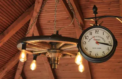 a clock hanging from a ceiling with a fan at 