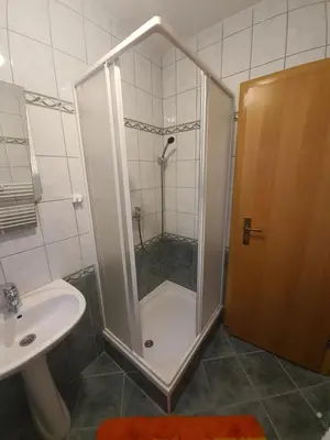 a shower with a glass door next to a sink and a toilet at Apartman M. Rados in Kupres