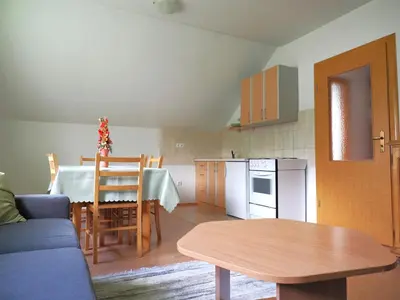 a living room with a table and a kitchen at Apartman M. Rados in Kupres