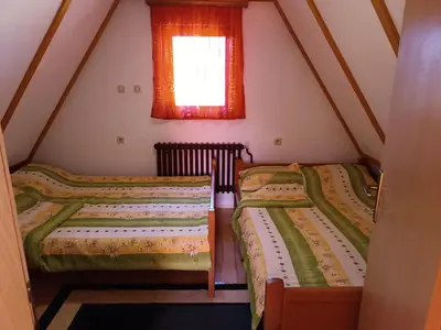 two beds in a attic room with a window at Apartmani ( VILA ) Vucko in Vlasic