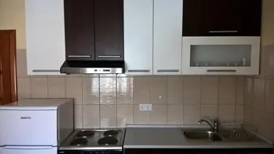 a kitchen with white cabinets and a sink and a microwave at Apartman Vesna in Kupres