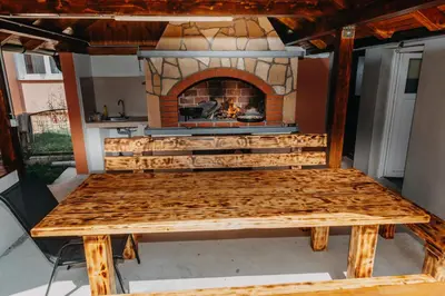 a picnic table with a fireplace on a patio at Apartman Vesna in Kupres