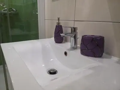 a bathroom sink with a purple soap dispenser on it at Brilliant Apartman in Bihać