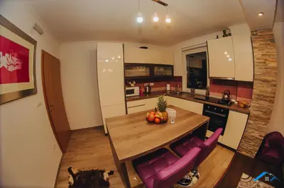 a kitchen with a wooden table and purple chairs at Brilliant Apartman in Bihać