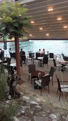a patio with tables and chairs next to the water at Apartman River Una in Bihać