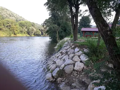 a river with a gazebo on the side of it at Hostel Topić in Banja Luka