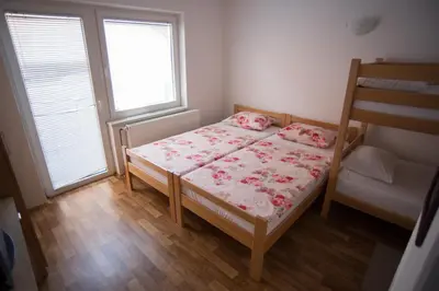 a small bedroom with a bed and two windows at Hostel Larisa in Banja Luka