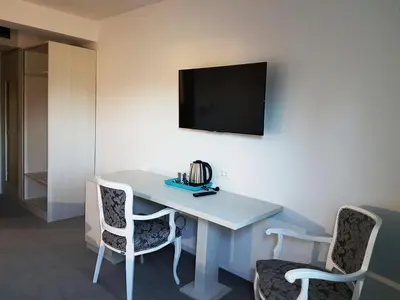 a room with a table with two chairs and a television at Hotel SAX Gračanica in Gračanica