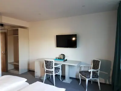 a room with a desk and two chairs and a tv on the wall at Hotel SAX Gračanica in Gračanica