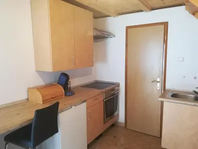 a kitchen with wooden cabinets and a black chair at Vacation Home Pliva in Šipovo