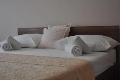 a bed with white pillows and a wooden headboard at Apartman Visoko in Visoko