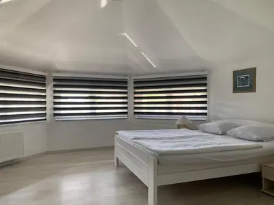 a white bedroom with a bed and some windows at Villa Goldlux in Bihać