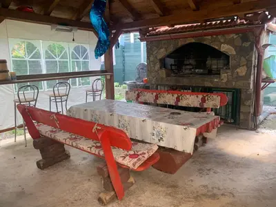 a table and bench in front of a stone oven at Villa Goldlux in Bihać